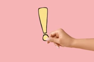 黄色のビックリマークを持つ女性の手