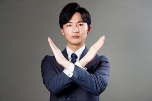 胸の前でバツサインをする男性